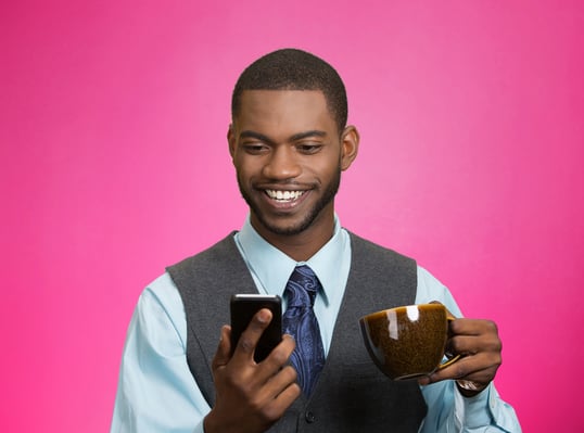 Closeup portrait happy, smiling business man reading good news on smart phone, lawyer holding mobile, drinking cup coffee isolated pink background. Human face expression, emotion, corporate executive Closeup portrait happy, smiling business man reading good news on smart phone, lawyer holding mobile, drinking cup coffee isolated pink background. Human face expression, emotion, corporate executive